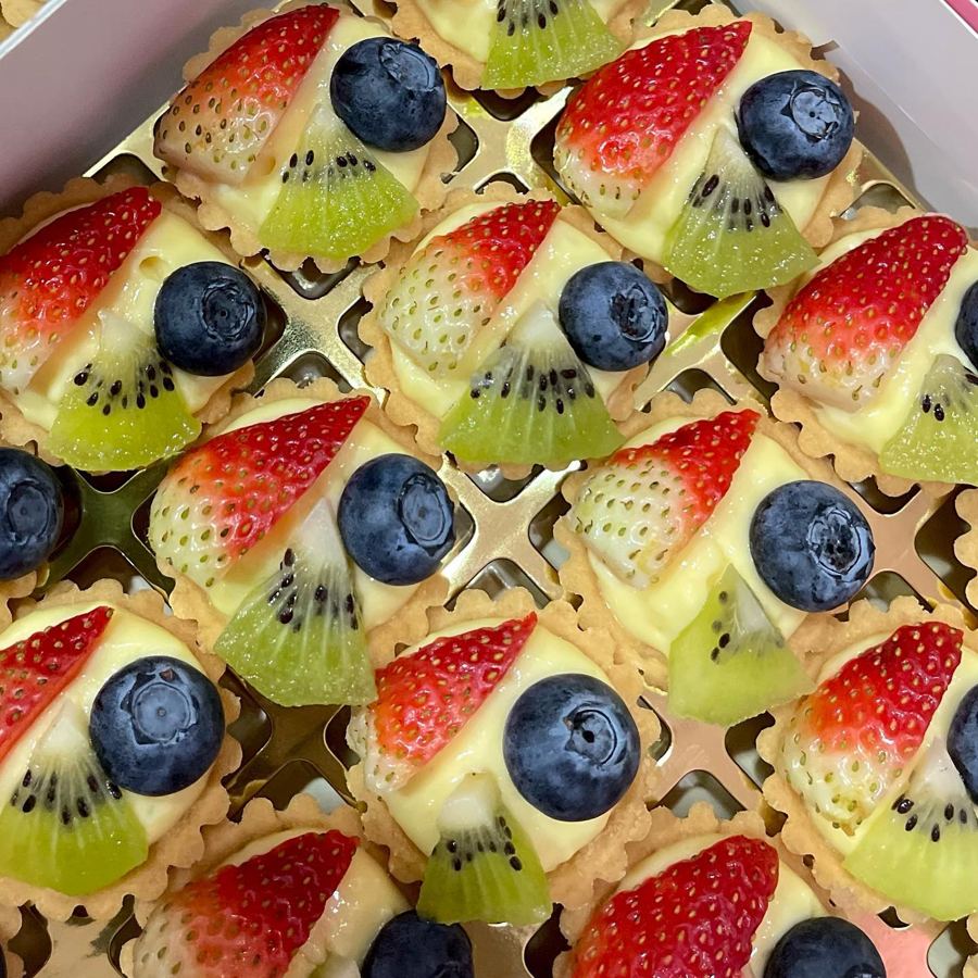 Tray of custard fruit tarts topped with strawberry, blueberry and kiwi