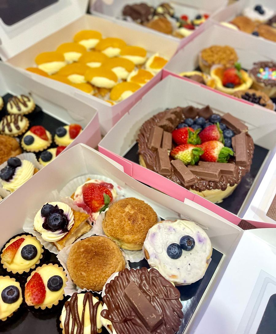Gift boxes filled with cheesetarts, cream puffs and a fruit-topped chocolate cake