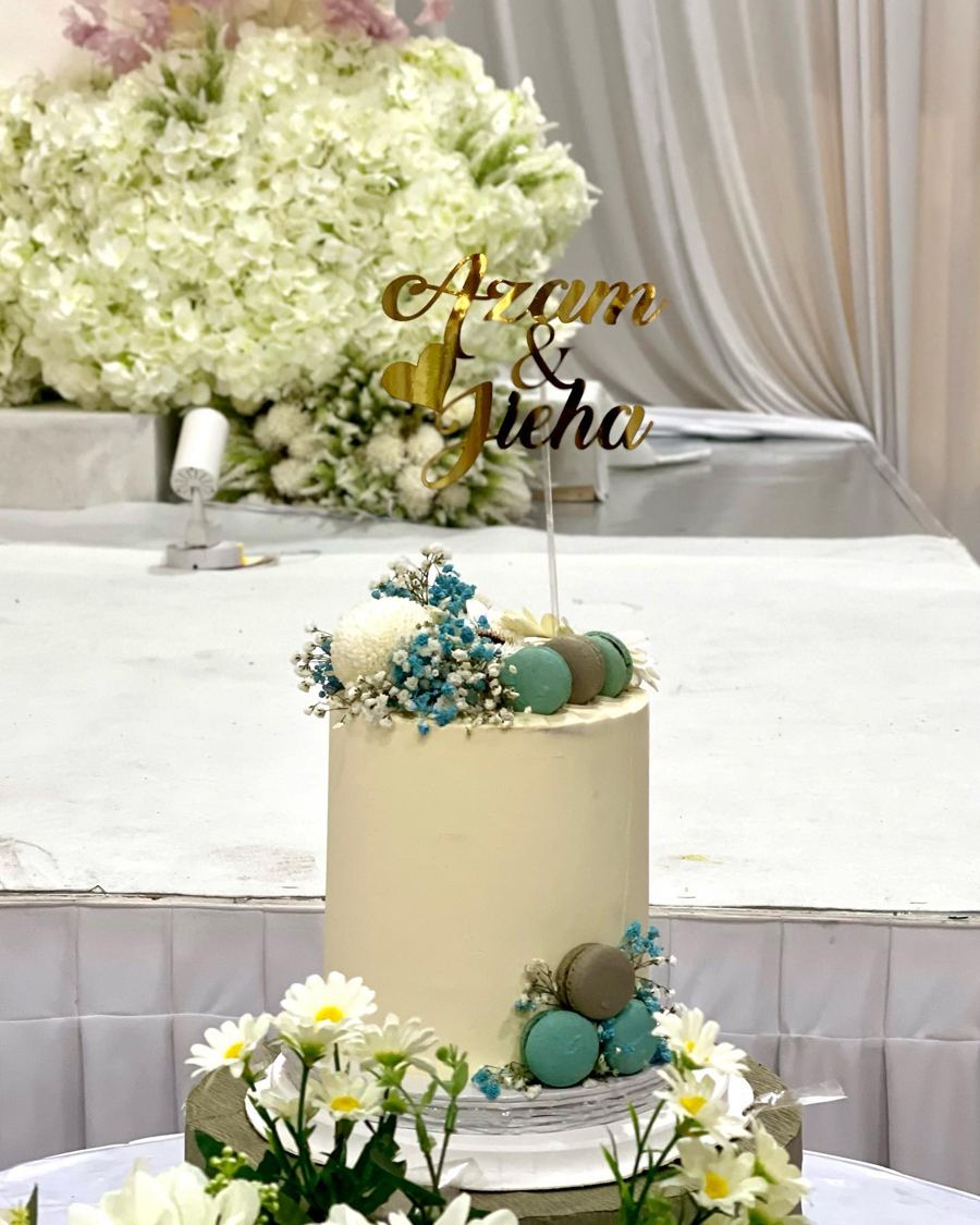 Tall cream wedding cake decorated with macarons and fresh flowers